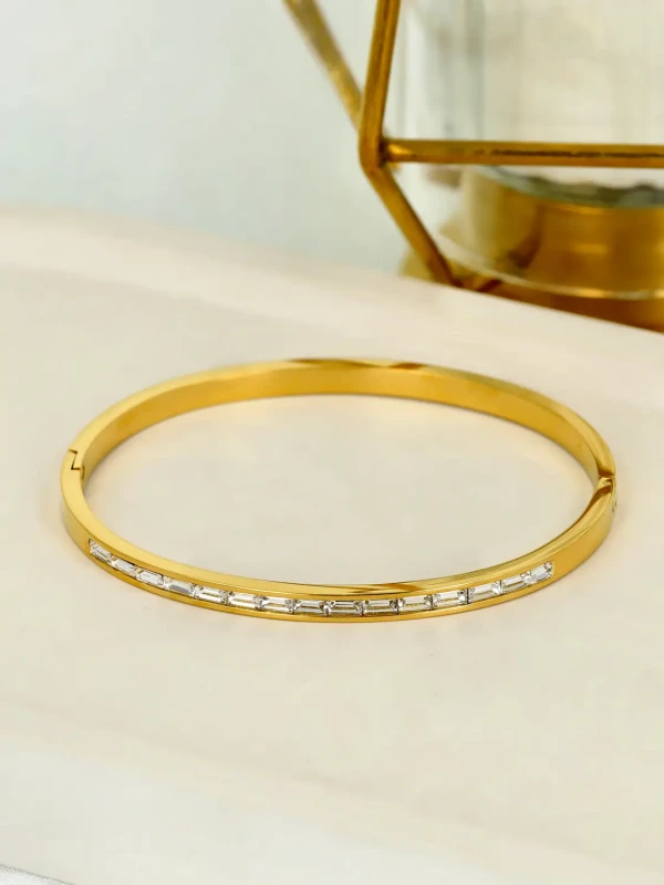 Pozłacana bransoletka sztywna typu bangle z cyrkoniami szlifu bagietkowego